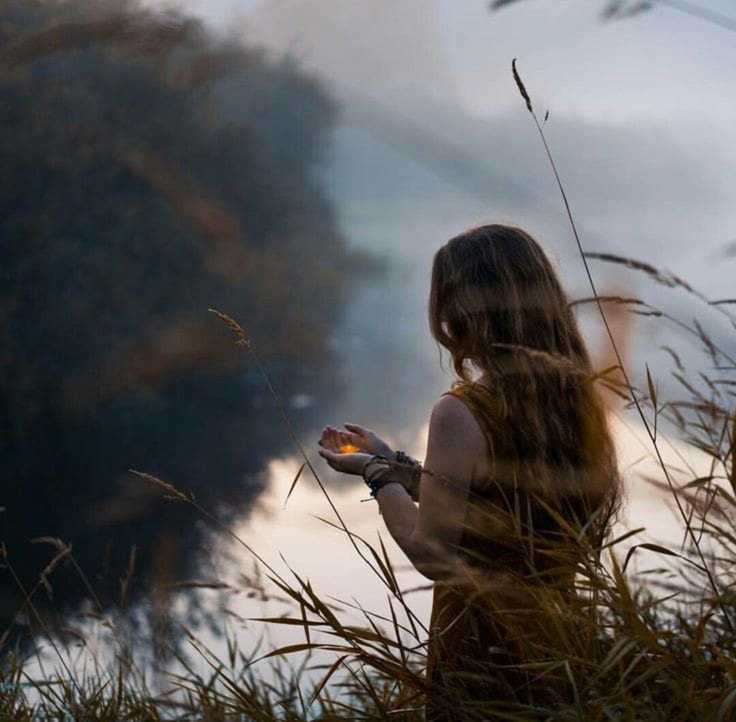 Femme avec dans les mains une bougie à côté des roseaux