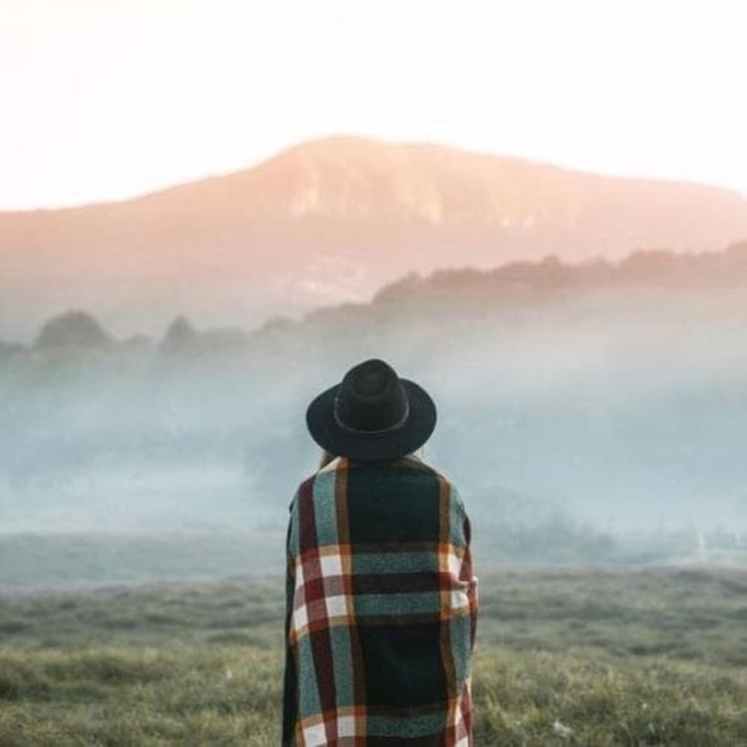 femme devant montagne avec couverture et chapeau